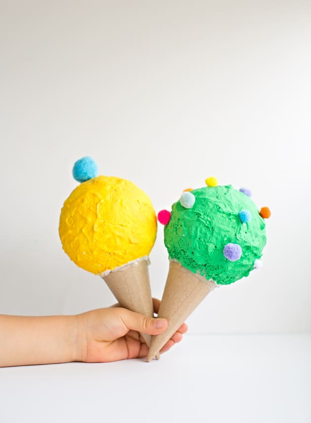 Prace plastyczne z lodami to w tym wypadku rożki lodowe z masy papier mache. Na zdjęciu widzimy dwa lody w żółtym i zielonym kolorze.