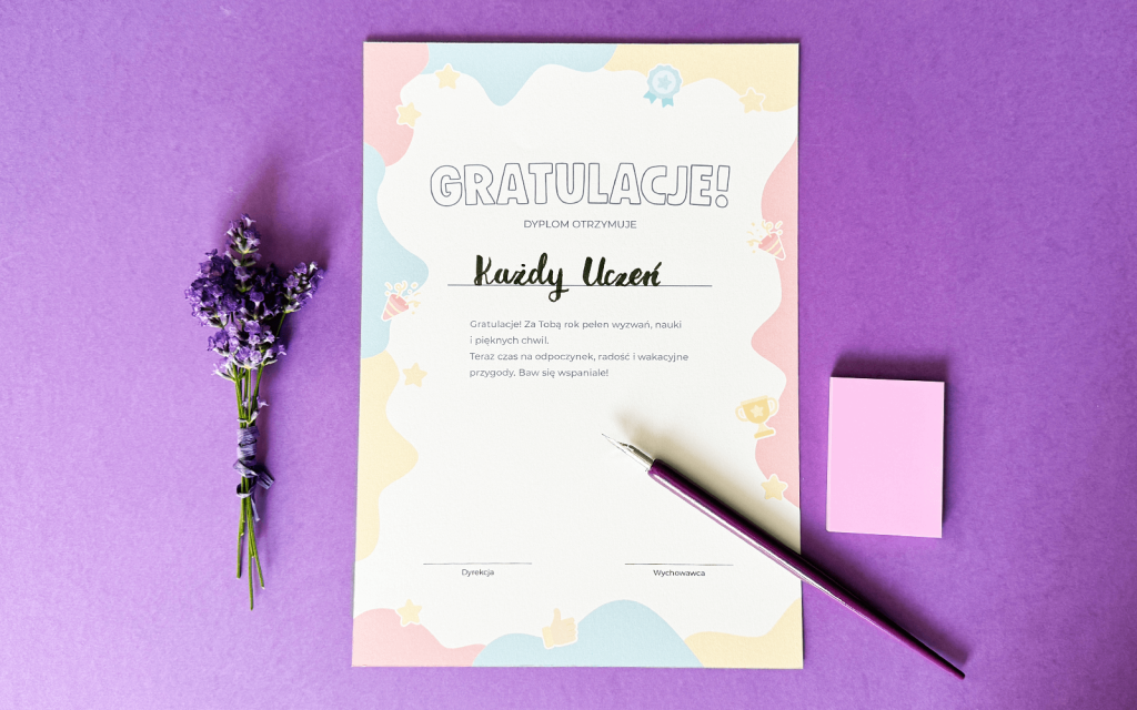 Dyplom gratulacyjny w pastelowych barwach na jaskrawym fioletowym tle, obok bukiecik lawendy i notesik z karteczkami samoprzylepnymi, a na dyplomie pozostawione pióro.